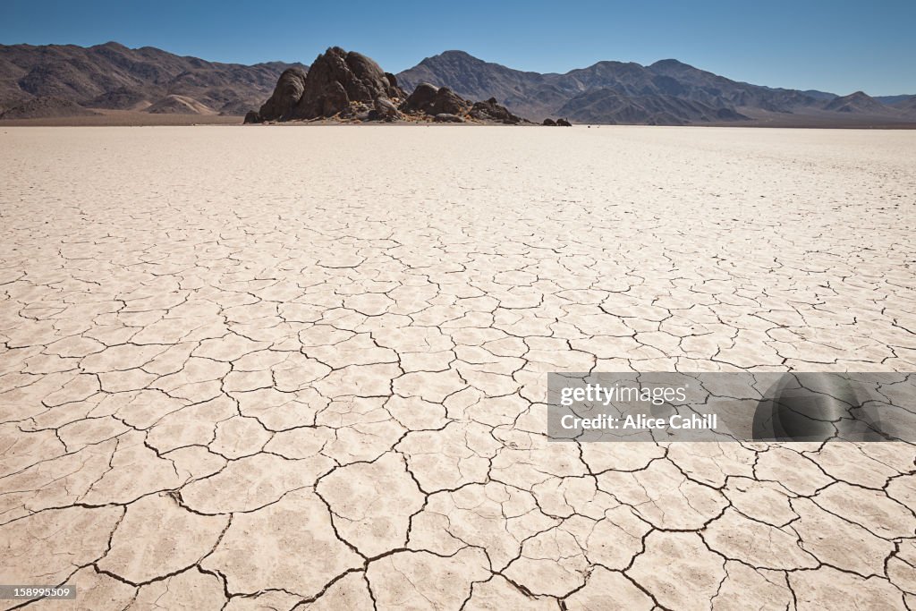 Pattern of dry mud on lakebed, distant mountians.