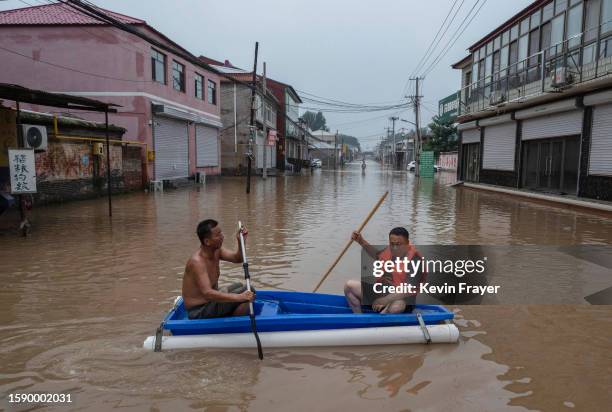 Local residents paddle a makeshift boat as they help others in an area inundated with floodwaters on August 3, 2023 near Zhuozhou, Hebei Province...