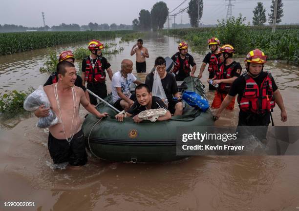Local residents are helped in a boat to safety by rescuers in an area inundated with floodwaters on August 3, 2023 near Zhuozhou, Hebei Province...
