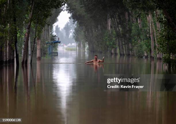 Local resident gestures as he walks in chest deep floodwaters towards a rescue boat to be helped to safety in an area inundated with floodwaters on...