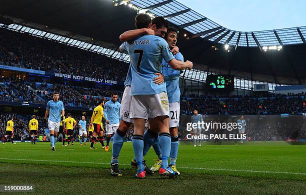 Manchester City's English midfielder Gareth Barry celebrates with Spanish midfielder David Silva and English midfielder James Milner after scoring...