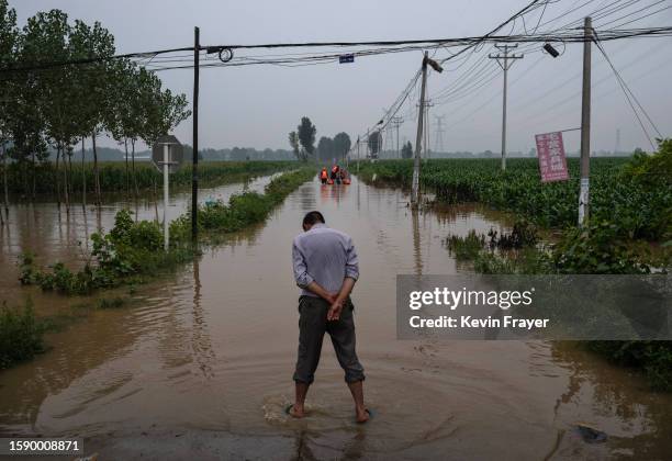 Local resident waits for others to arrive with rescuers at the launch area for boats in an area inundated with floodwaters on August 3, 2023 near...