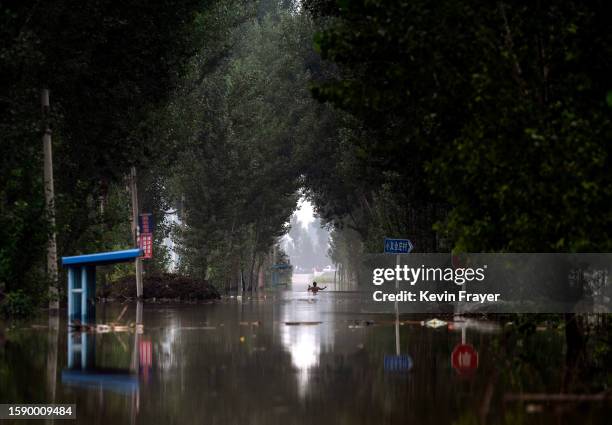Local resident gestures s he waits in chest deep floodwaters for a rescue boat to be helped to safety in an area inundated with floodwaters on August...