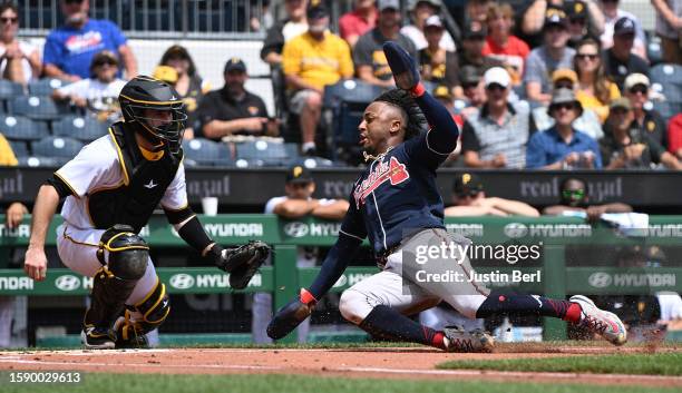 Ozzie Albies of the Atlanta Braves slides in safely past Jason Delay of the Pittsburgh Pirates to score on a RBI single by Austin Riley in the first...