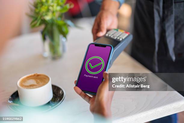 customer paying for her coffee via a banking app - brand name mobile payment foto e immagini stock