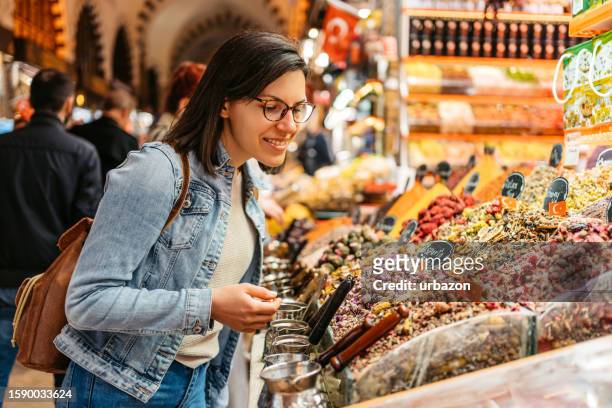 young woman looking at dried tea leaves at the grand bazaar in istanbul - istanbul food stock pictures, royalty-free photos & images