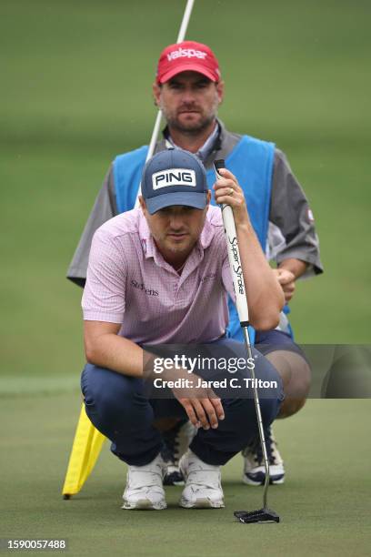 Austin Cook of the United States lines up a putt with his caddie on the tenth green during the first round of the Wyndham Championship at Sedgefield...