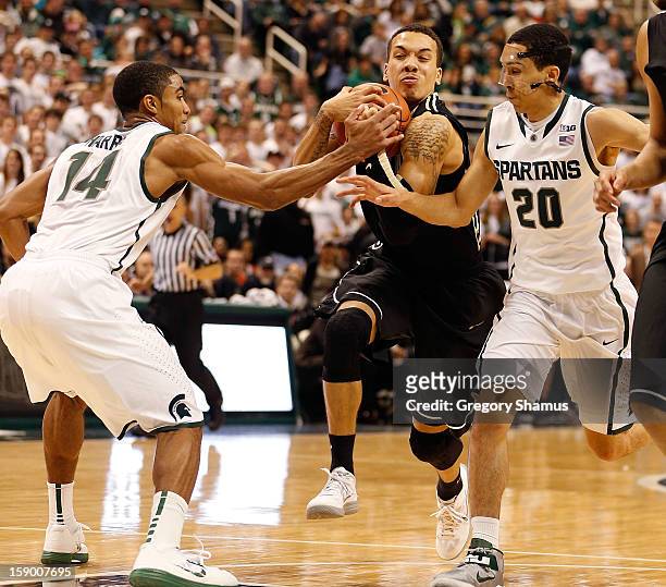 Anthony Johnson of the Purdue Boilermakers tries to split the defense of Travis Trice and Gary Harris of the Michigan State Spartans at the Jack T....
