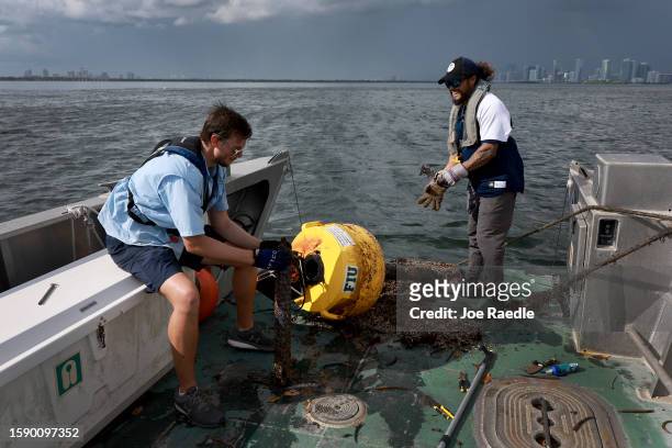 Bradley Schonhoff and Nick Evans conduct routine maintenance on a research buoy in Biscayne Bay on August 03, 2023 in Miami, Florida. Evans is...
