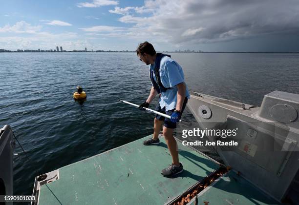 Bradley Schonhoff uses a pole to grab a research buoy to conduct routine maintenance on it in Biscayne Bay on August 03, 2023 in Miami, Florida....