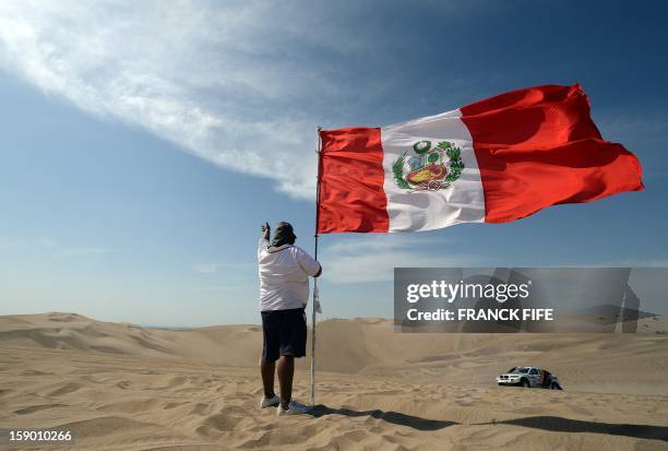 Peruvian man holds a national flag during the Stage 1 of the Dakar 2013 between Lima and Pisco, Peru, on January 5, 2013. The rally will take place...