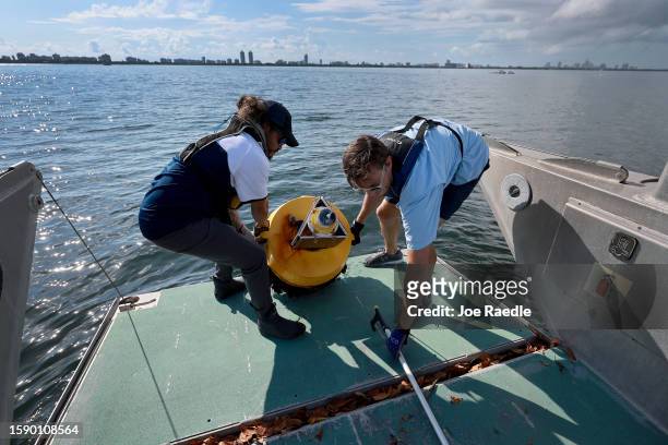 Nick Evans and Bradley Schonhoff conduct routine maintenance on a research buoy in Biscayne Bay on August 03, 2023 in Miami, Florida. Evans is...