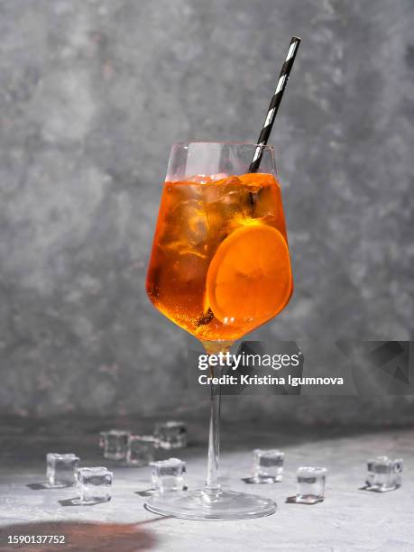 aperol syringe with straw and orange slice and ice. italian alcoholic drink, aperitif - aperol spritz stock pictures, royalty-free photos & images