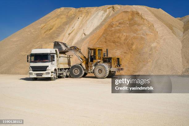 backhoe loading sand into truck at quarry at work - gravel quarry stock pictures, royalty-free photos & images