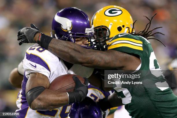 Running back Adrian Peterson of the Minnesota Vikings runs the ball as he is hit by outside linebacker Erik Walden of the Green Bay Packers in the...