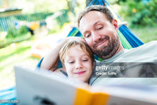 vater mit sohn entspannt sich im freien - hängematte stock-fotos und bilder