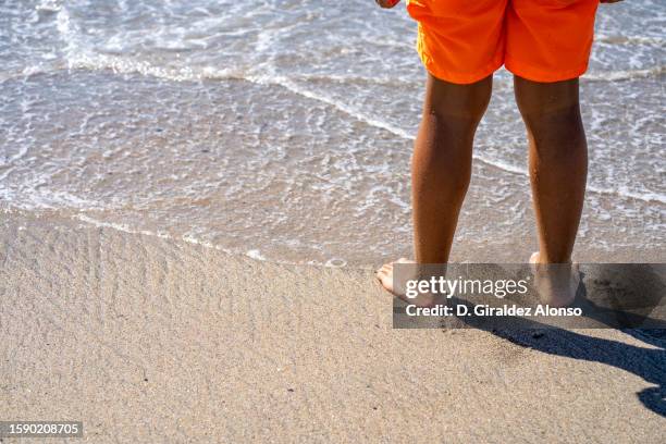 sea wave washing boys  feet - multi coloured trousers stock pictures, royalty-free photos & images