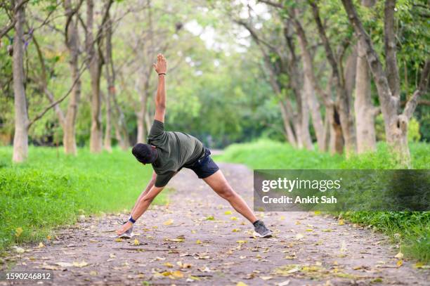 young athlete man doing morning exercise and practicing parivrtta trikonasana or triangle pose yoga - parivrtta trikonasana stock pictures, royalty-free photos & images