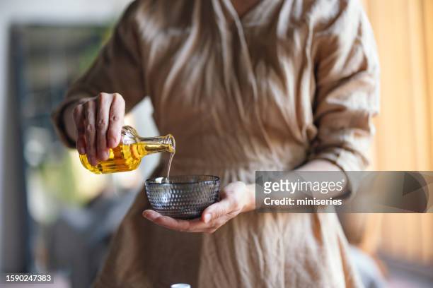 mujer anónima bebiendo aceite en un tazón en el spa - massage room fotografías e imágenes de stock