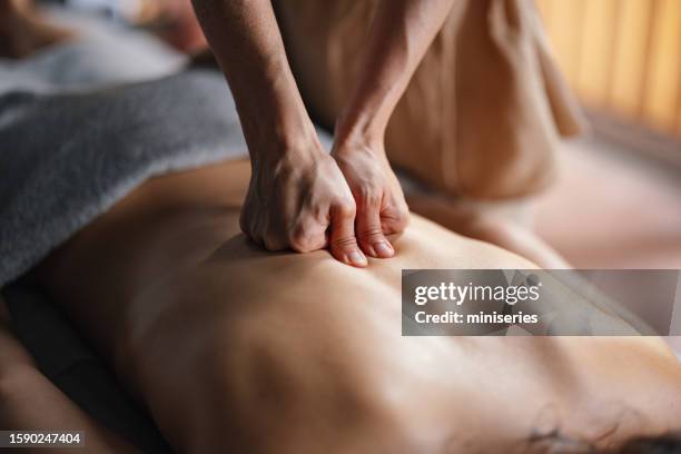 anonymous massage therapist massaging an unrecognizable woman’s back - healing hands stockfoto's en -beelden