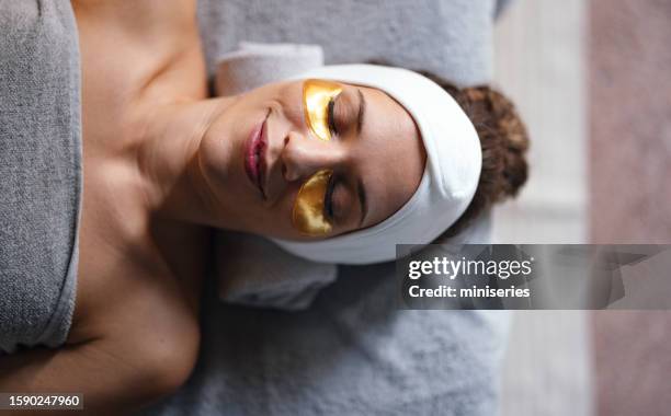 retrato de una hermosa mujer sonriente disfrutando de relajarse con una máscara para los ojos - massage room fotografías e imágenes de stock