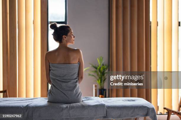 bella donna che si siede sul lettino da massaggio presso la spa - centro benessere stabilimento termale foto e immagini stock