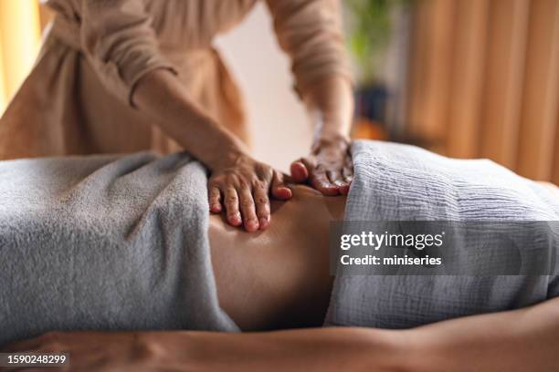 terapeuta de masaje femenina anónima masajeando el vientre de una mujer en el spa - massage room fotografías e imágenes de stock