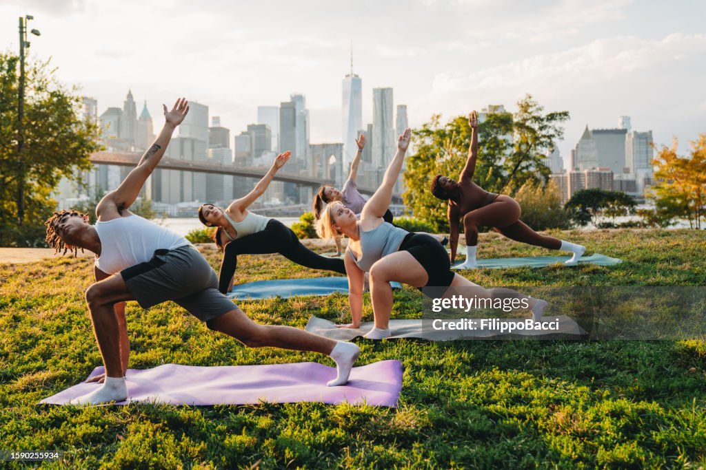 Yoga class in the city at sunset with New York City skyline in the background