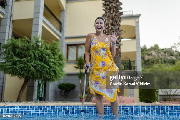 behinderte frau, die spaß am pool hat - gehgips stock-fotos und bilder