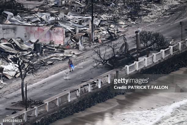 An aerial image taken on August 10, 2023 shows a person walking down Front Street past destroyed buildings burned to the ground in Lahaina in the...