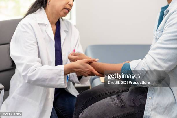 unrecognizable female doctor gently moves unrecognizable male patient's arm - wrist stock pictures, royalty-free photos & images
