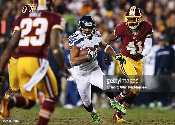 Clinton McDonald of the Seattle Seahawks carries the ball against the defense of Madieu Williams and DeAngelo Hall of the Washington Redskins during...