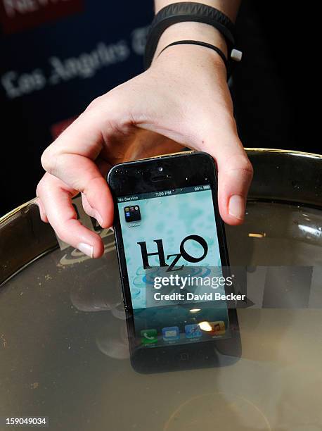 An iPhone using HzO Waterblock technology is displayed in a bowl of water during a press event at the Mandalay Bay Convention Center for the 2013...