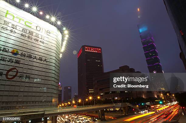 Traffic moves past a billboard advertisement for HTC Corp.'s One X+ smartphone, left, and the Taipei 101 building, right, in Taipei, Taiwan, on...