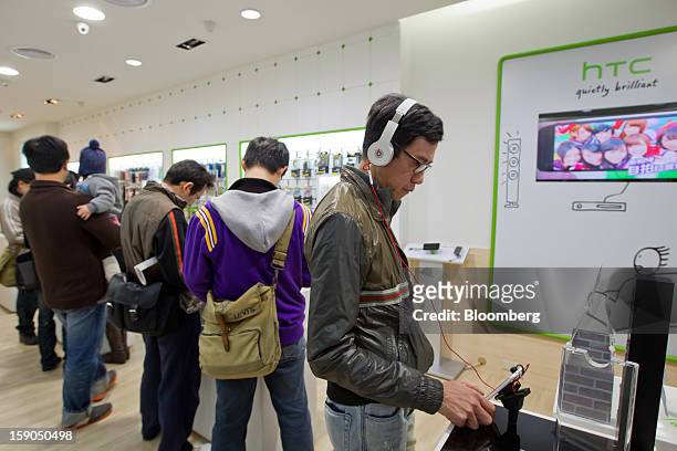 Customer, right, tries out an HTC Corp. One X+ smartphone at one of the company's stores in Taipei, Taiwan, on Sunday, Jan. 6, 2013. HTC is scheduled...