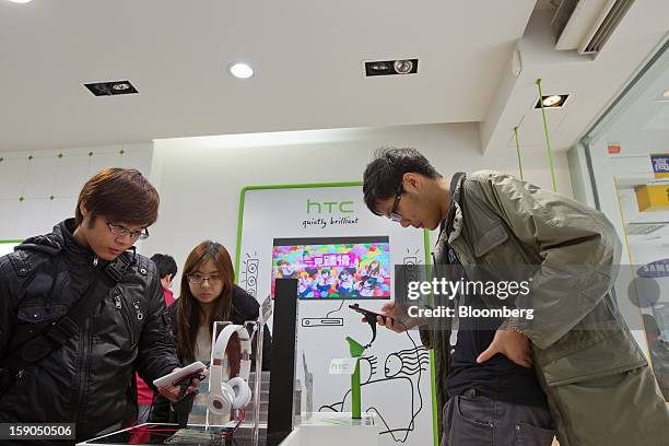 Customers try out HTC Corp. Smartphones at one of the company's stores in Taipei, Taiwan, on Sunday, Jan. 6, 2013. HTC is scheduled to release...