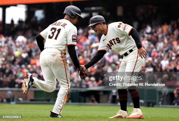 LaMonte Wade Jr. #31 of the San Francisco Giants is congratulated by third base coach Mark Hallberg after Wade Jr. Hit a solo home run against the...