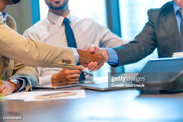 businessmen shaking hands at the board room table.. - lawyer handshake stock pictures, royalty-free photos & images