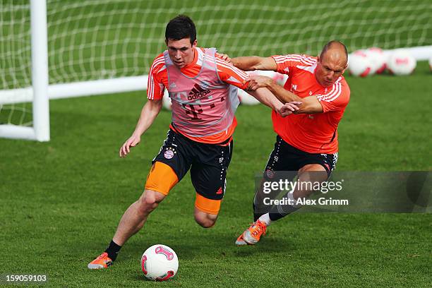 Pierre-Emile Hojbjerg is challenged by Arjen Robben during a Bayern Muenchen training session at the ASPIRE Academy for Sports Excellence on January...