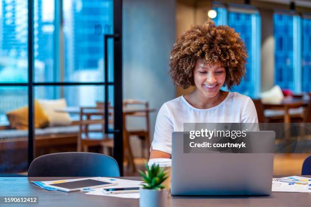 junge frau, die an einem laptop in einem modernen büro arbeitet - digitales marketing stock-fotos und bilder