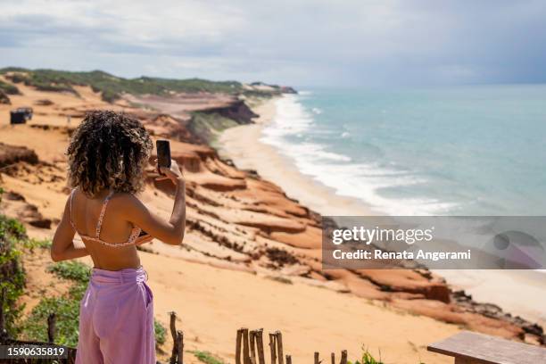 jeune femme photographiant la plage pendant les vacances - natal brésil photos et images de collection
