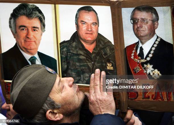 Serbian Radical party supporter kisses photos of war crimes suspects Radovan Karadzic , Ratko Mladic and Vojislav Seselj at the party rally in...