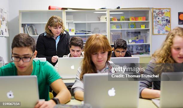 Pupils with their teacher, working at their lap-tops during a lesson at the Heinrich-Mann-School in the Neukoelln district of Berlin, Germany on...