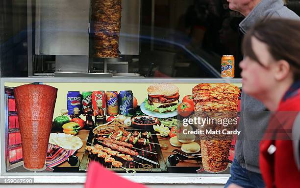 People pass a poster advertising fast food outside a takeaway food shop on January 7, 2013 in Bristol, England. A government-backed TV advert - made...