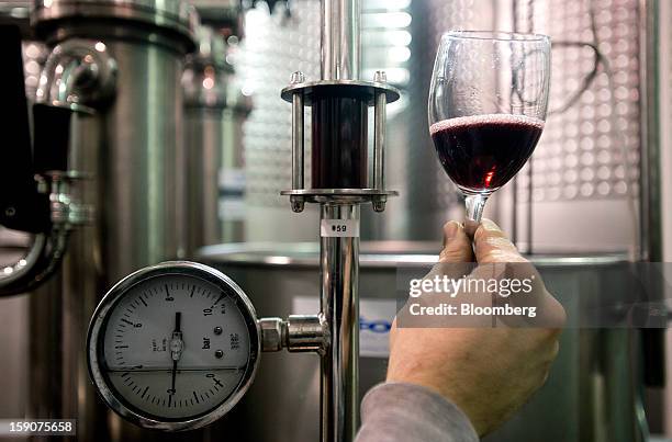 Worker checks the color of a red wine in a glass after going through the filtration system at the Ferrante Winery in Geneva, Ohio, U.S., on Friday,...