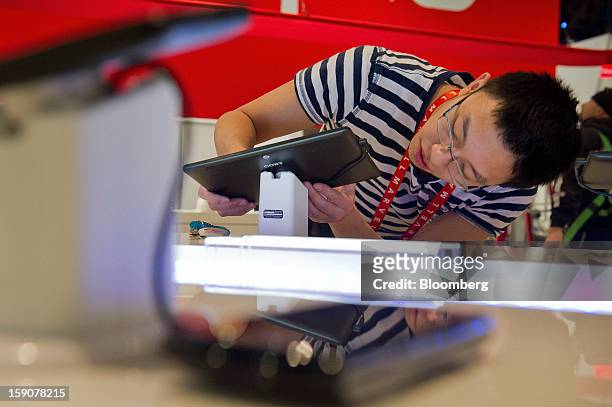 Coby Electronics Corp. Employee Yancy Hu installs a tablet computer prior to the 2013 Consumer Electronic Show in Las Vegas, Nevada, U.S., on Monday,...