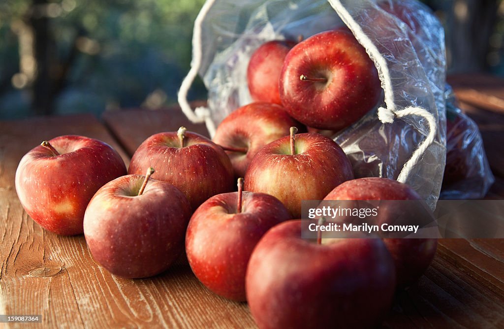 Apples and a sack on a wooden table outdoors