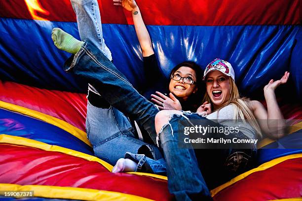 happy young women on a bouncy slide - bouncy castle stock pictures, royalty-free photos & images