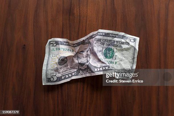 crumpled u.s. five dollar bill on a wooden desk - nota de cinco dólares americanos - fotografias e filmes do acervo