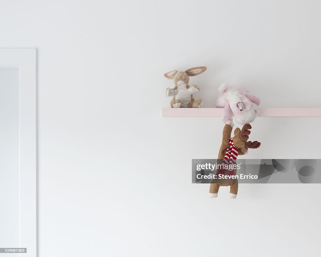 A soft toy unicorn helping a deer up onto a shelf